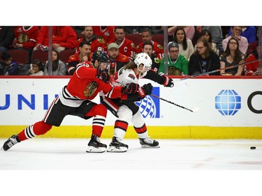 Tomas Jurco of the Blackhawks and Erik Karlsson of the Senators battle for position as they chase the puck.