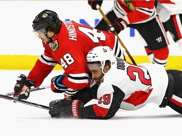 Johnny Oduya and Vinnie Hinostroza hit the ice as they battle for the puck.