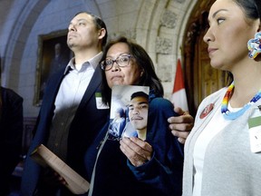 Debbie Baptiste holds up a photo of her son Colten Boushie, as the family spoke to reporters in the Foyer of the House of Commons after a day of meetings on Parliament Hill, in Ottawa on Tuesday, Feb. 13, 2018.
