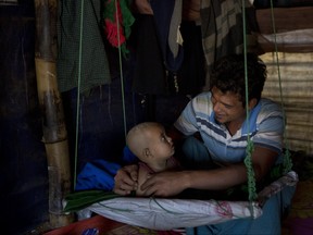 In this Jan. 21, 2018 photo, Rohingya Muslim refugee Noor Kadir, 24, from the Myanmar village of Gu Dar Pyin, plays with his son inside the family makeshift shelter in Balukhali refugee camp, Bangladesh. (AP Photo/Manish Swarup)