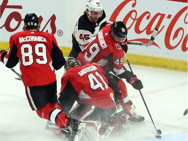 Ottawa Senators Christopher DiDomenico (49) clears the puck from behind goaltender Craig Anderson (41) as New Jersey Devils Sami Vatanen (45) and Senators Max McCormick look on during first period NHL hockey in Ottawa, Tuesday, February 6, 2018 .