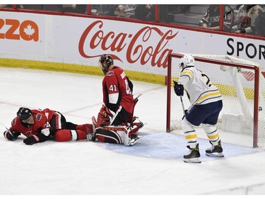 The Ottawa Senators' Mark Borowiecki looks past goaltender Craig Anderson as the puck enters the net off a shot by the Buffalo Sabres' Scott Wilson (not shown), as Sabres' Jason Pominville looks on in the first period.