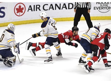 The Ottawa Senators' Mark Stone launches himself past the Buffalo Sabres' Marco Scandella in an attempt to gain control of the puck.