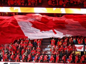 A giant Canadian flag moves across the crowd above the Calgary Flames bench during the national anthem ahead of a playoff game on April 19, 2017.