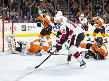 The Senators' Derick Brassard controls the puck as he heads toward Philadelphia Flyers goalie Alex Lyon after getting away from Nolan Patrick, right.