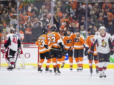 Philadelphia's Scott Laughton, third from left, gets a hug by Claude Giroux after tipping in a shot for a third-period goal against the Senators.