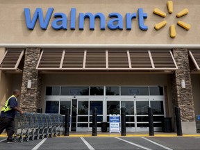 A worker pushes shopping carts in front of a Walmart store in La Habra, Calif., on May 9, 2013. Walmart announced Wednesday that it will no longer sell firearms and ammunition to people younger than 21.