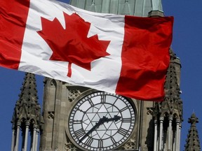 In this file photo, a Canadian flag from West Block on Parliament Hill waves in front of the Peace Tower, in Ottawa on Mar. 24, 2011.