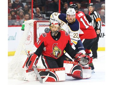 Craig Anderson of the Ottawa Senators follows the puck as Johan Larsson the Buffalo Sabres looks on.