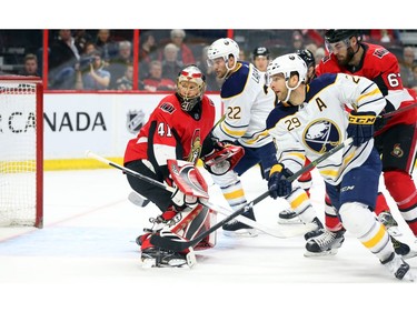 Craig Anderson of the Ottawa Senators follows the puck (not in picture) as Johan Larsson (22) and #29 Jason Pominville of the Buffalo Sabres chase the play.