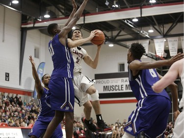 Carleton's T.J. Lall, middle, goes to the basket against Ryerson's Tanor Ngom. David Kawai/Postmedia