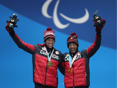 Gold medallist Brian McKeever of Canada and guide Russell Kennedy signal to the crowd during the medal ceremony for the visually impaired men's 1.5-kilometre cross-country sprint.