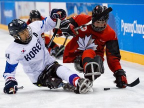 Ottawa's Ben Delaney, right, battles for the puck with Seung Hwan Jung of Korea in Thursday's para ice hockey semifinal at Pyeongchang.
