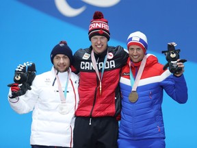 Gold medallist Mark Arendz of Canada. centre, silver medallist Benjamin Daviet of France, left, and bronze medallist Nils-Erik Ulset of Norway celebrate during the medal ceremony for the men's standing biathlon 12.5-kilometre race on Friday.