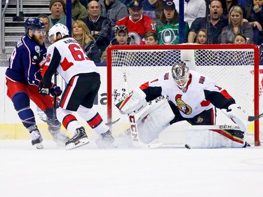 Senators captain Erik Karlsson (65) pushes David Savard of the Blue Jackets out of the crease as netminder Mike Condon makes a save during the first period.
