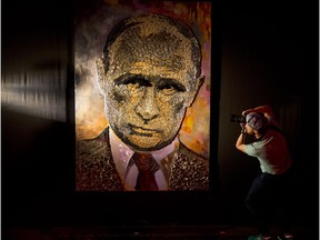 A photographer take a photo of a portrait of Russian President, Vladimir Putin, made by Ukrainian artist Dasha Marchenko, out of cartridge cases, during a presentation in an art gallery in Kiev, Ukraine, Tuesday, Aug. 25, 2015.