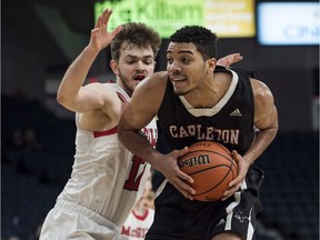 Carleton Ravens' Eddie Ekiyor, right, drives to the basket in front of McGill Redmen's Noah Daoust in the bronze medal game of the U Sports men's basketball national championship in Halifax on Sunday, March 11, 2018.