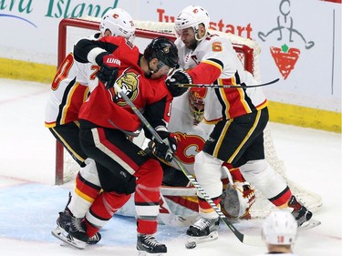 Flames centre Curtis Lazar, left, and defenceman Mark Giordano check Senators winger Alexandre Burrows in front of the net during the second period.