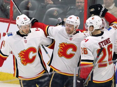 Calgary centre Matt Stajan (18) celebrates with defenceman Brett Kulak and Michael Stone after scoring to make it 2-0 in the third period of Friday's game against the Senators.