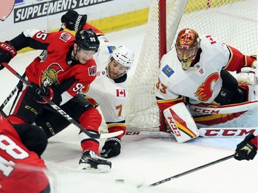 Senators centre Matt Duchene, left, and Flames defenceman T.J. Brodie (7) battle for the puck as goaltender David Rittich (33) looks on during the third period.