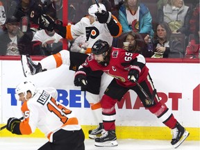 Ottawa Senators defenceman Erik Karlsson sends Philadelphia Flyers centre Travis Konecny into the boards.