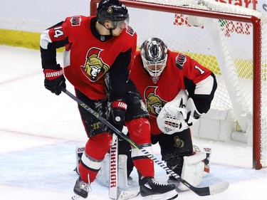 Ottawa Senators goaltender Mike Condon (1) makes a save against the New York Islanders as teammate Mark Borowiecki (74) defends during first period NHL hockey in Ottawa, Tuesday, March 27, 2018 .