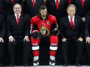 Ottawa Senators captain Erik Karlsson sits alongside team owner Eugene Melnyk, second from left, as they take part in the annual team photo in Ottawa on Wednesday, March 7, 2018. (THE CANADIAN PRESS/Sean Kilpatrick)