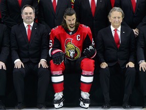 Ottawa Senators captain Erik Karlsson sits alongside team owner Eugene Melnyk, second from left, as they take part in the annual team photo in Ottawa on Wednesday, March 7, 2018.