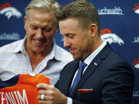 Case Keenum, front, admires his new jersey as John Elway, general manager of the Denver Broncos, looks on during a news conference to introduce him as the new starting quarterback Friday, March 16, 2018, in Englewood, Colo. (AP Photo/David Zalubowski)