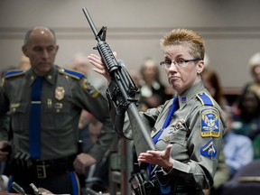 In this Jan. 28, 2013, file photo, firearms training unit Detective Barbara J. Mattson, of the Connecticut State Police, holds up a Bushmaster AR-15 rifle, the same make and model of gun used by Adam Lanza in the Sandy Hook School shooting, during a hearing of a legislative subcommittee in Hartford, Conn.