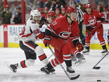Carolina Hurricanes' Brock McGinn (23) and Ottawa Senators' Mike Hoffman (68) chase the puck during the first period of an NHL hockey game in Raleigh, N.C., Monday, March 26, 2018.