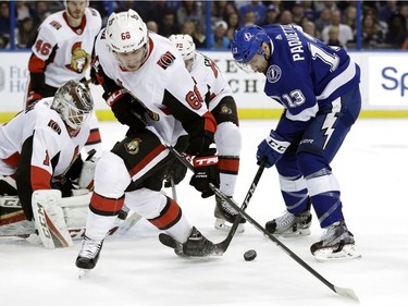 Ottawa Senators left wing Mike Hoffman (68) and Tampa Bay Lightning center Cedric Paquette (13) battle for the puck in front of goaltender Mike Condon during the second period of an NHL hockey game Tuesday, March 13, 2018, in Tampa, Fla.