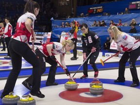Canada second Shannon Birchard, left, and lead Dawn McEwen sweep in a rock as skip Jennifer Jones, right, and Japan skip Tori Koana look on at the World Women's Curling Championship in North Bay, Ont., on Friday, March 23, 2018.