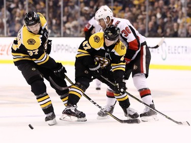 Colin White of the Senators tries to squeeze past the Bruins' Torey Krug (47) as Patrice Bergeron collects the puck during the second period.
