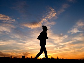 A jogger is silhouetted against the morning sky.