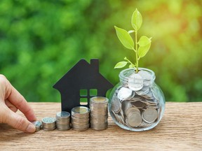 growth sprout plant in jar with full of coins and hand holding stack of coins with paper house as property or mortgage investment concept