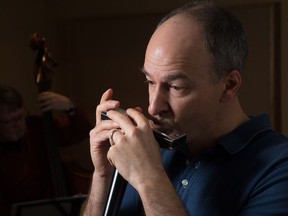 Normand Glaude playing the harmonica while rehearsing with his quartet for an upcoming performance.