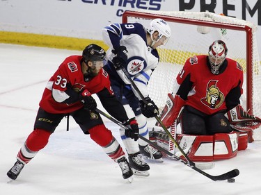 Ottawa Senators Fredrik Claesson (33) and Winnipeg Jets Andrew Copp (9) struggle for the puck in front of Senators goaltender Craig Anderson (41) during first period NHL hockey action at the Canadian Tire Centre in Ottawa on Monday, April 2, 2018.