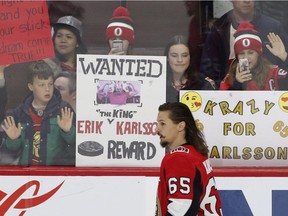 Fans hold up signs in support of Senators captain Erik Karlsson (65) during the warm-up before Monday's home game against the Jets.