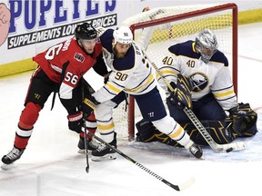 Buffalo's Ryan O'Reilly (90) pushes Ottawa's Magnus Paajarvi away from the puck as goaltender Robin Lehner covers it up during a March 8 game in Ottawa.