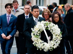 The father of Lingzi Lu, Jun Lu, foreground left, and her aunt Helen Zhao, foreground right, carry a wreath ahead of the family of Martin Richard, background from left, Henry, Bill, Denise and Jane, partially hidden, during a ceremony at the site where Martin Richard and Lingzi Lu were killed in the second explosion at the 2013 Boston Marathon, Sunday, April 15, 2018, in Boston. (AP Photo/Michael Dwyer)