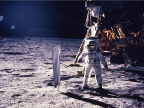 n this July 20, 1969 file photo provided by NASA, astronaut Edwin E. Aldrin Jr. walks on the surface of the moon, with seismogaphic equipment that he just set up. The flag like object on a pole is a solar wind experiment and in the background is the Lunar Landing Module.