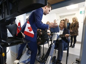 Norwegian ambassador to Canada Anne Kari Hansen Ovind (sitting right) tries out the Motitech,  the real-life bicycle ride at the Élisabeth Bruyère Hospital, Friday .