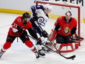 Ottawa Senators' Fredrik Claesson and Winnipeg Jets' Andrew Copp struggle for the puck during NHL action at the Canadian Tire Centre in Ottawa on April 2, 2018