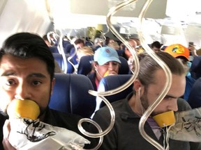 FILE- In this April 17, 2018, file photo provided by Marty Martinez, Martinez, left, appears with other passengers after a jet engine blew out on the Southwest Airlines Boeing 737 plane he was flying in from New York to Dallas, resulting in the death of a woman who was nearly sucked from a window during the flight. Video inside the cabin of the recent Southwest flight that lost cabin pressure above 30,000 feet shows many passengers improperly placing oxygen masks on their faces, putting their lives at risk.