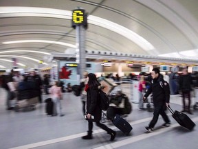FILE: People carry luggage at Pearson International Airport.
