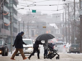 People cross the street as they trudge through falling hail, snow, and rain in Toronto, Ontario on Saturday, April 14, 2018. THE CANADIAN PRESS/Cole Burston