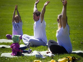 16-month old Penelope Doull-Hoffman keeps an eye on her mom, Jenny Doull, practicing yoga along with her dad Jonathan Hoffman and sister nine-year-old Mae Doull-Hoffman who were in Rockcliffe Park Saturday May 12, 2018.