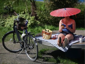 A woman shelters from the sun under a parasol.