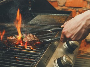 Man cooking meat steaks on professional grill outdoors